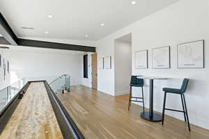 Bar featuring light wood-style flooring, recessed lighting, and light stone countertops
