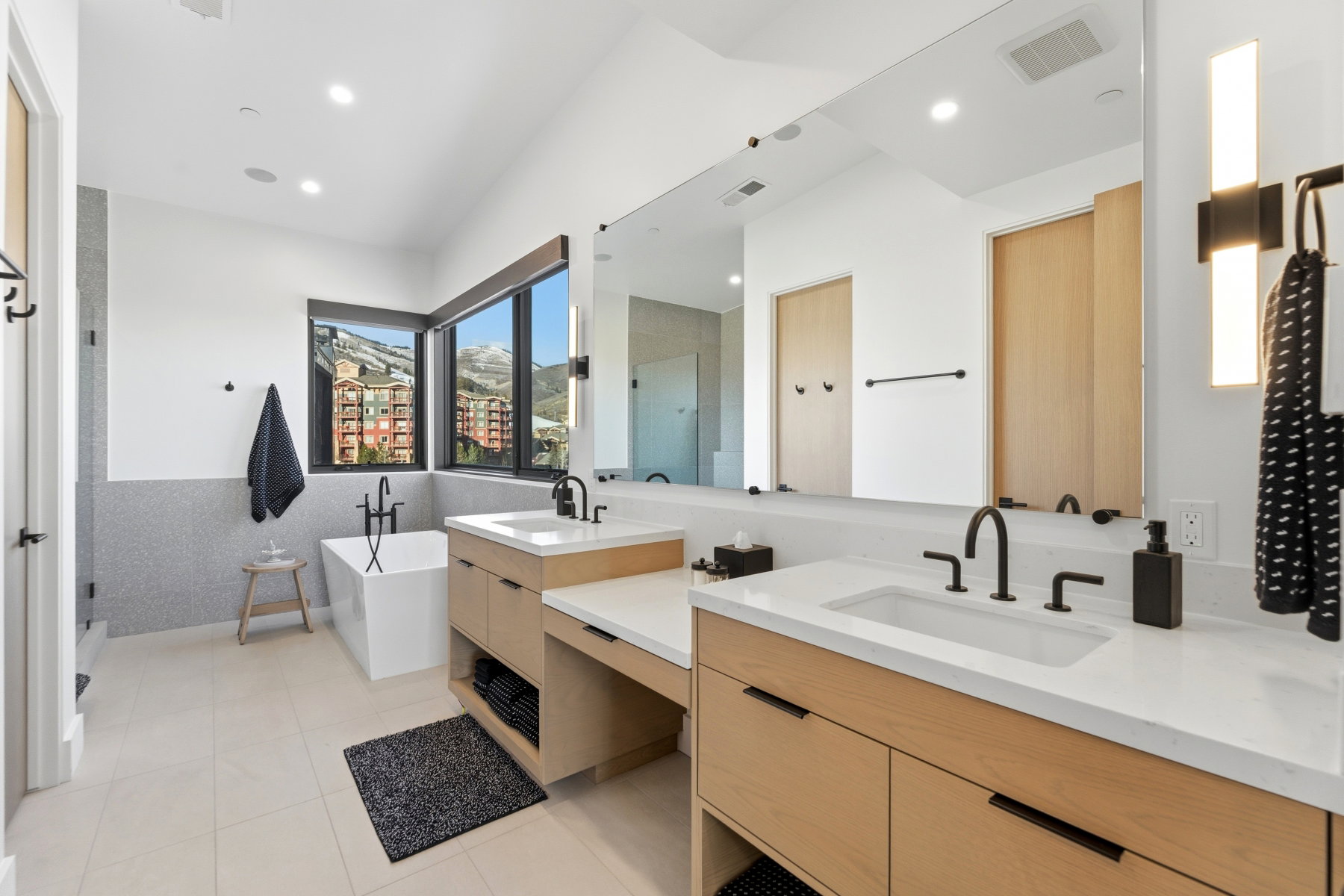 Full bathroom featuring double vanity, a stall shower, a freestanding bath, light tile patterned floors, and recessed lighting