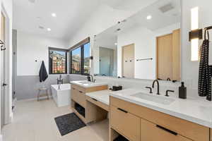 Full bathroom featuring double vanity, a stall shower, a freestanding bath, light tile patterned floors, and recessed lighting