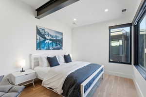 Bedroom with light wood-style floors, beamed ceiling, and recessed lighting