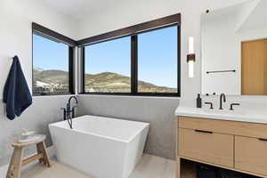 Full bath featuring healthy amount of natural light, a soaking tub, vanity, and a mountain view