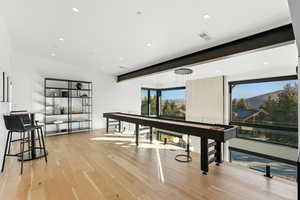 Recreation room featuring light wood finished floors, recessed lighting, and beamed ceiling