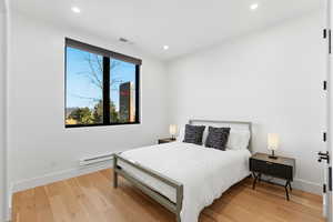 Bedroom featuring light wood-style floors, a baseboard heating unit, and recessed lighting