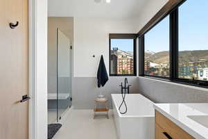Full bathroom with a soaking tub, a shower with door, vanity, and light tile patterned flooring