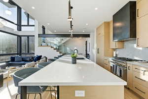 Kitchen with light brown cabinetry, a kitchen breakfast bar, a large island, stainless steel range with gas cooktop, and light wood-style flooring