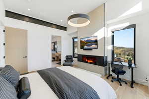 Bedroom with light wood-style floors, a fireplace, and ensuite bathroom