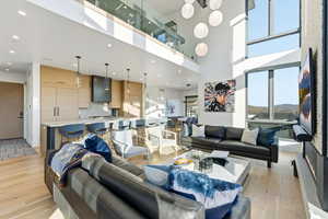 Living room with light wood-style flooring, a high ceiling, and recessed lighting