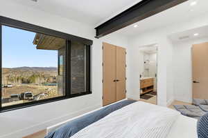 Bedroom with a mountain view, ensuite bath, a closet, and wood finished floors