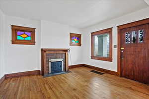 Unfurnished living room with a tiled fireplace and hardwood / wood-style flooring
