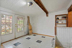 Entryway with beam ceiling, french doors, and tile patterned floors