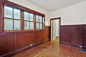 Spare room with wainscoting, wood-type flooring, and wood walls