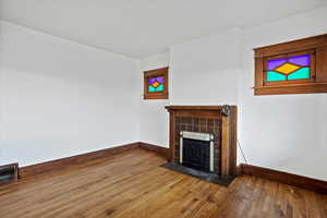 Unfurnished living room with a tiled fireplace and hardwood / wood-style flooring