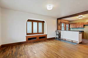 Unfurnished living room with dark wood-style floors and beamed ceiling