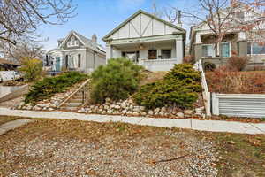 View of front of home featuring a porch, brick siding, and stairway