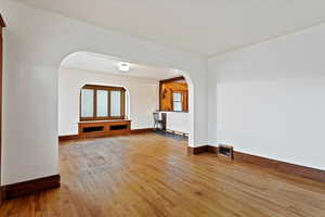 Unfurnished living room with hardwood / wood-style flooring and arched walkways