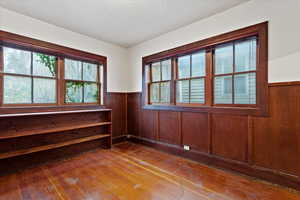Unfurnished room with wainscoting, plenty of natural light, hardwood / wood-style floors, and wood walls