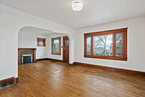 Foyer featuring arched walkways, hardwood / wood-style floors, healthy amount of natural light, and a fireplace