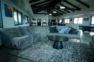 Living room with wood finished floors, high vaulted ceiling, and beamed ceiling