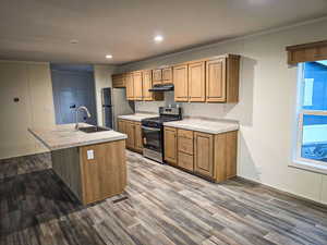 Kitchen with appliances with stainless steel finishes, light countertops, a kitchen island with sink, recessed lighting, and dark wood finished floors