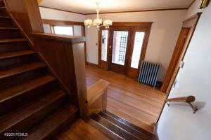Staircase with radiator heating unit, wood finished floors, and a chandelier