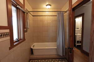 Bathroom featuring shower / bath combination with curtain and dark tile patterned floors