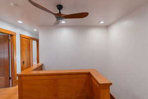 Hall with recessed lighting and an upstairs landing