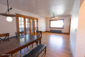 Dining space featuring wood finished floors, french doors, radiator heating unit, and a ceiling fan