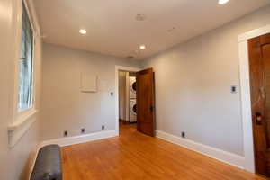 Empty room with wood finished floors, recessed lighting, and stacked washer / drying machine