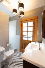 Full bath with vanity, a tile shower, and tile walls