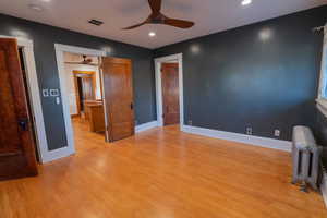 Unfurnished bedroom featuring radiator heating unit, light wood-type flooring, a ceiling fan, and recessed lighting