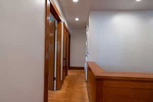 Hall with recessed lighting, light wood-style flooring, and stacked washer / drying machine