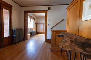 Entrance foyer featuring radiator heating unit, ornamental molding, and hardwood / wood-style floors