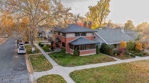 View of front facade featuring a front lawn, a chimney, and a sunroom