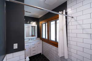 Full bathroom with vanity, tile walls, and dark tile patterned flooring