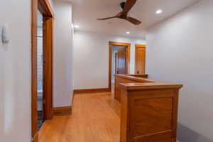 Hallway with light wood-style flooring and recessed lighting