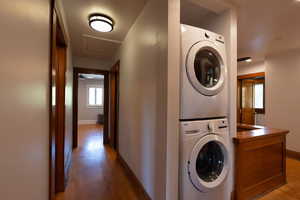 Laundry room with light wood-style flooring, estacked washer and dryer, and radiator heating unit