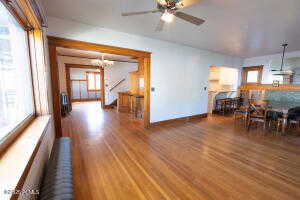 Living room with a chandelier, radiator heating unit, wood finished floors, and a ceiling fan