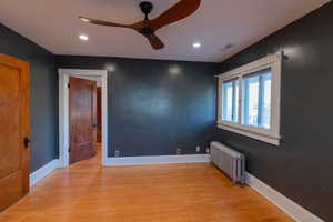 Spare room with radiator heating unit, light wood-style flooring, a ceiling fan, and recessed lighting