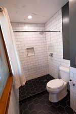 Full bath featuring a shower stall, dark tile patterned flooring, tile walls, and recessed lighting