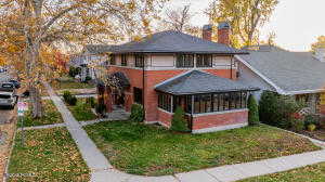 View of front of house featuring a sunroom, a chimney, and a front lawn