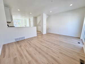 Unfurnished room with light wood finished floors, recessed lighting, stairs, and a chandelier