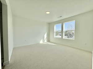 Carpeted empty room with a textured ceiling and baseboards