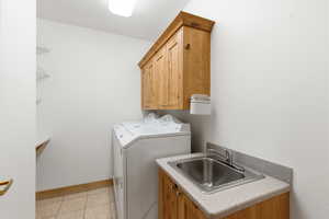Washroom with light tile patterned floors, washer and clothes dryer, and cabinet space