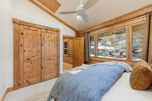 Bedroom with rustic walls, a closet, vaulted ceiling, carpet, and ceiling fan