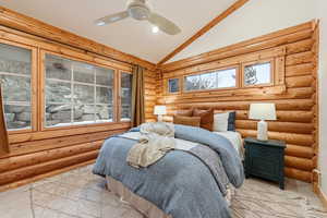 Bedroom with rustic walls, vaulted ceiling, and a ceiling fan