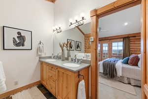 Bathroom featuring rustic walls, double vanity, ensuite bathroom, and ceiling fan