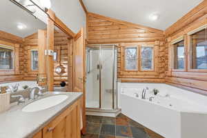 Bathroom with a bath, vaulted ceiling, a shower stall, log walls, and vanity