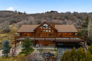Back of property with a chimney, log exterior, and roof with shingles