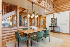 Dining room featuring log walls, light wood-style flooring, and a chandelier