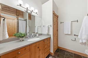 Bathroom with vanity, curtained shower, and stone tile floors